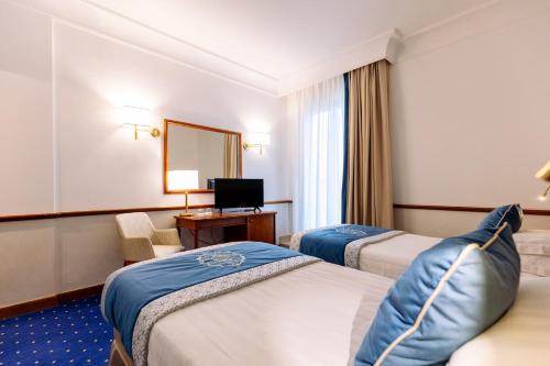 a hotel room with two beds and a television at Grand Hotel Terme & Spa in Montegrotto Terme