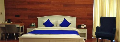 a bedroom with a bed with blue pillows and a chair at Polo Cherrapunjee Resort in Cherrapunji