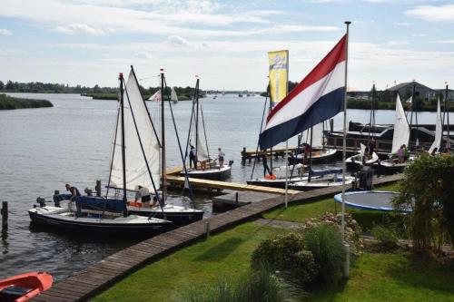 a group of boats docked at a dock with a flag at Het Toppunt groot vakantiehuis aan het water in Sneek