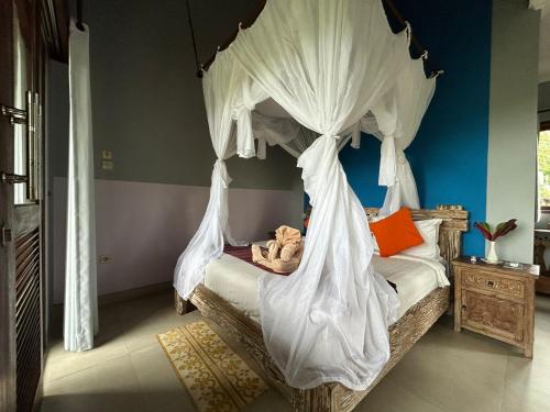 シデメンにあるPondok Damai Sidemenのベッドルーム(白いカーテン付きの天蓋付きベッド1台付)