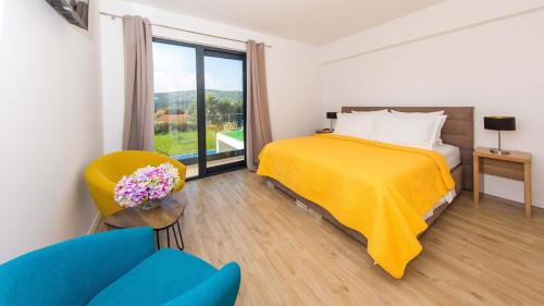 ein Schlafzimmer mit einem Bett, einem Stuhl und einem Fenster in der Unterkunft Stylish villa near Dubrovnik with a swimming pool in Mlini
