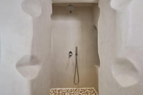 a shower with a hose in a white bathroom at Myconian Princess in Mikonos
