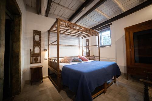 a bedroom with a canopy bed with a blue blanket at Corte Signoretti - Hystorical Villa in Canale Monterano
