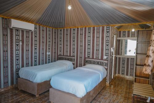 two beds in a room with a wall at Hasan Zawaideh Camp in Wadi Rum