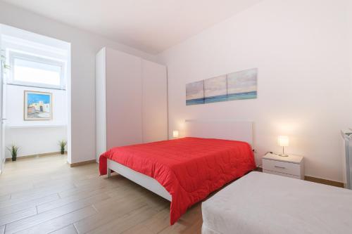 ein weißes Schlafzimmer mit einem roten Bett und zwei Fenstern in der Unterkunft Casa Vacanza Messina in Messina