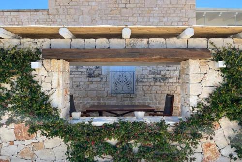 eine Steinmauer mit einem Tisch und einer Bank in der Unterkunft Trulli Harmonia con piscina - Alberobello in Alberobello