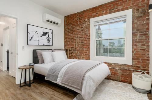 een slaapkamer met een bed en een bakstenen muur bij The Broad in Columbus