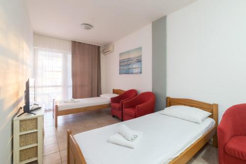 a bedroom with a bed and two red chairs at Hotel Rooms Roccia in Novigrad Dalmatia