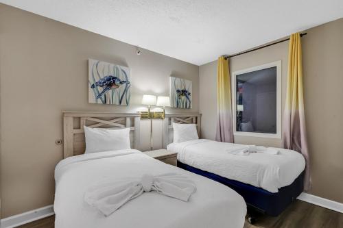 a room with two beds with white sheets and a window at Beachfront Condo in Atlantica Resort with Pool in Myrtle Beach