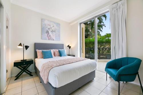 a bedroom with a bed and a blue chair at Iconic Chevron Renaissance Private Apartments in Gold Coast