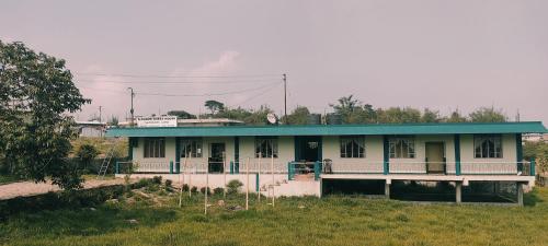 a house with a blue roof in a field at D Cloud Guesthouse in Cherrapunji