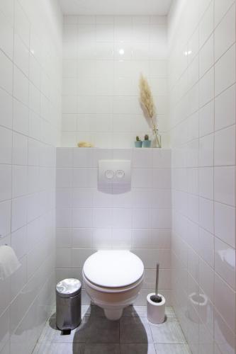 a bathroom with a toilet in a white tiled room at Het Toppunt groot vakantiehuis aan het water in Sneek