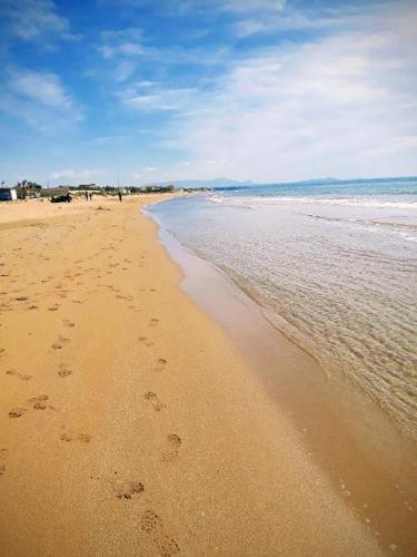 a beach with footprints in the sand and the water at Villa Sunshine in Triscina