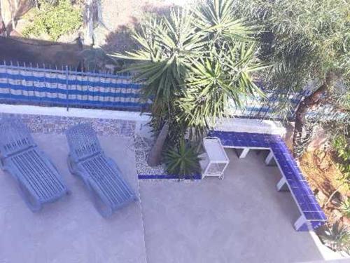 three blue chairs and a bench next to a fence at Villa Sunshine in Triscina