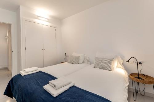 - une chambre blanche avec 2 lits et des serviettes dans l'établissement LA GOLA APARTMENT, First-line Beachfront, Newly Refurbished, à Port de Pollença