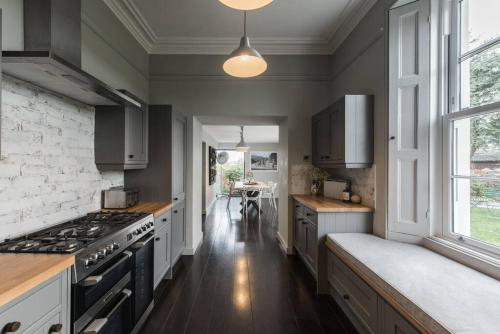 uma cozinha com armários brancos e um forno com placa de fogão em The Surveyors House Devon, Luxury Victorian Villa in Torbay em Kingskerswell