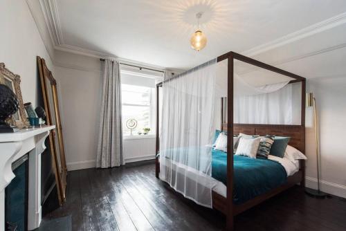 um quarto com uma cama de dossel e uma janela em The Surveyors House Devon, Luxury Victorian Villa in Torbay em Kingskerswell