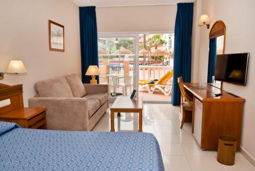 a living room with a bed a couch and a television at Bahía Tropical in Almuñécar