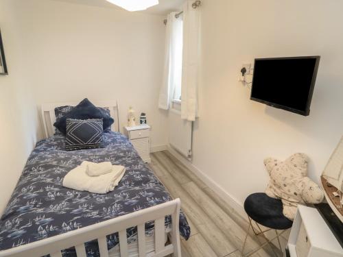 ein Schlafzimmer mit einem Bett, einem Fernseher und einem Stuhl in der Unterkunft Old Colliery Cottage in Shilbottle