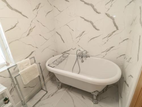 ein Badezimmer mit einem weißen Waschbecken und Marmorwänden in der Unterkunft Old Colliery Cottage in Shilbottle