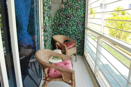 a balcony with wicker chairs and a wall with a window at Las Cayenas Residéncial in Santo Domingo