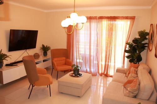 a living room with a couch and chairs and a tv at Las Cayenas Residéncial in Santo Domingo