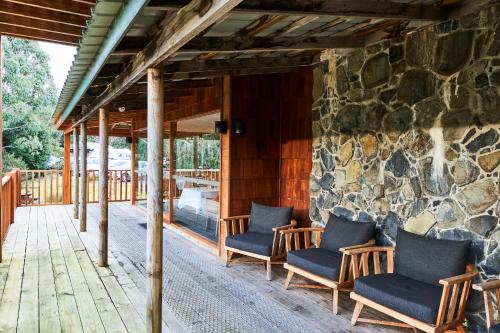 a porch with chairs and a stone wall at Peppers Cradle Mountain Lodge in Cradle Mountain