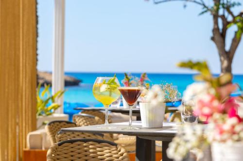 a table with two glasses of cocktails on a beach at Pavlo Napa Beach Hotel in Ayia Napa
