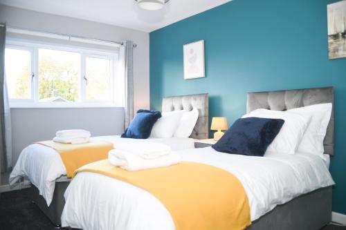 2 łóżka w pokoju z niebieskimi ścianami w obiekcie 2ndHomeStays -Willenhall-Charming 3-Bedroom Home w mieście Walsall