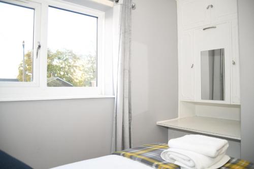 een witte badkamer met een raam en handdoeken op een bed bij 2ndHomeStays -Willenhall-Charming 3-Bedroom Home in Walsall