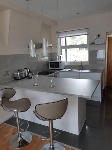a kitchen with two bar stools and a sink at Charming Mid Terrace Cottage in Conwy