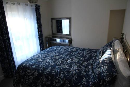 a bedroom with a bed with a blue bedspread and a window at Charming Mid Terrace Cottage in Conwy