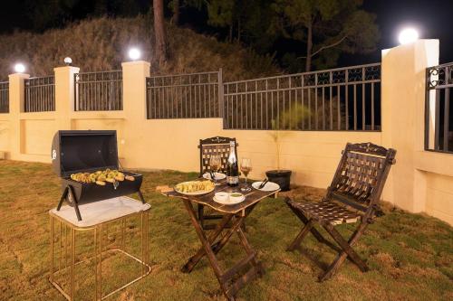 a patio with two chairs and a table and a grill at StayVista at Rolling Hills with Pool, Lawn & Pet Friendly in Tota Ām