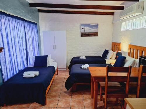 a room with two beds and a table and chairs at Swartberg Cottages in Prince Albert