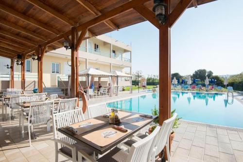 a patio with a table and chairs next to a pool at Barbie Hotel Apartments in Ialyssos