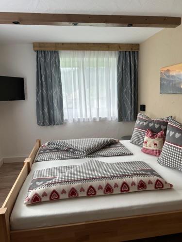 a large bed in a bedroom with a window at Ferienwohnungen LODGE-B in Weissenbach am Lech