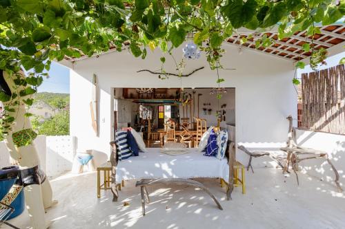 a room with a bed and chairs on a patio at Casa da Estrelinha - Ilha do Ferro in Gentileza