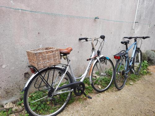 2 biciclette sono parcheggiate accanto a un muro di Maison COSY en pierre à Ars ad Ars-en-Ré