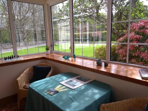 una mesa y sillas en una habitación con ventanas en Bridge of Bennie Cottage, en Banchory