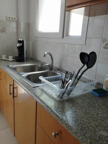 a kitchen sink with a dish rack and utensils at Mirina center apartments in Myrina