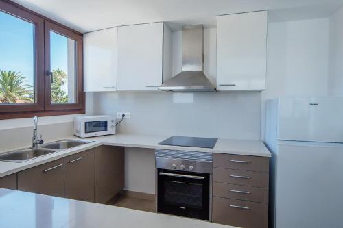 a white kitchen with a sink and a refrigerator at Aparthotel Caprice Skyline in Ciutadella