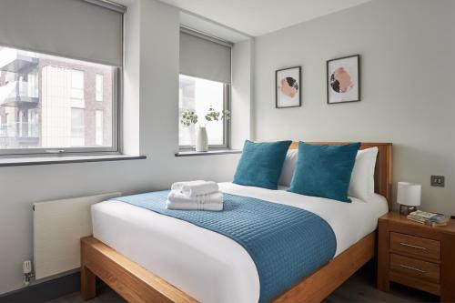 a bedroom with a large bed with blue pillows at Wembley Stadium by Viridian Apartments in London
