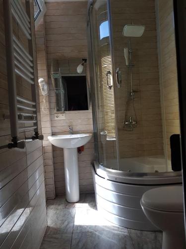 a bathroom with a sink and a shower and a toilet at Apartments NITA in Batumi