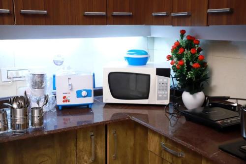 a kitchen with a counter with a microwave and flowers at Divine India Service Apartment 3 BHK D-198 Saket in New Delhi