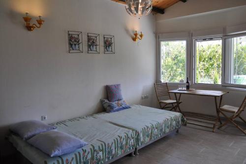 a bedroom with a bed and a table and windows at Fofi's garden in Litochoro