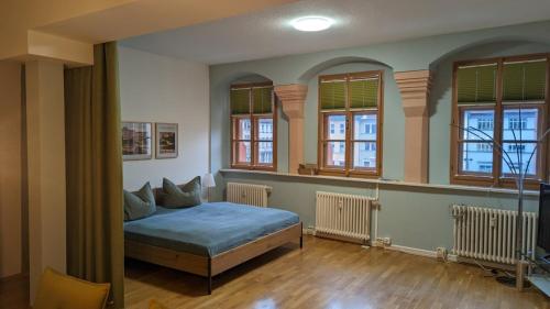 ein Schlafzimmer mit einem Bett in einem Zimmer mit Fenstern in der Unterkunft Appartment am Markt in Weimar