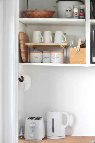 a cupboard filled with cups and other kitchen utensils at Zen hideaway in Aotea in Porirua