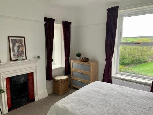 a bedroom with a fireplace and a bed and a window at North View House Next to Hadrian's Wall in Gilsland