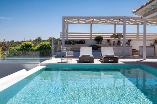 a swimming pool with two chairs and a pavilion at Alba Bianca Villa, a Secluded Retreat, By ThinkVilla in Hersonissos