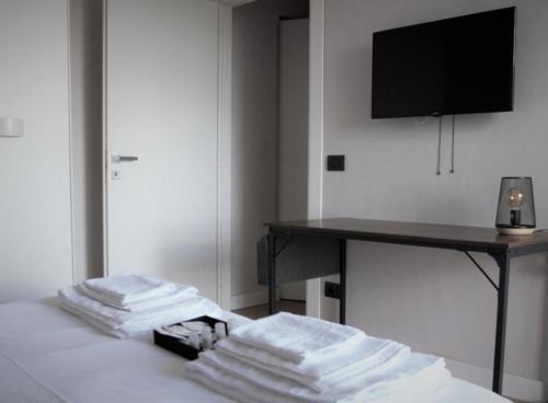 una pila de toallas sentadas en una cama con escritorio en 7 LAKES Aparthotel, en Burolo